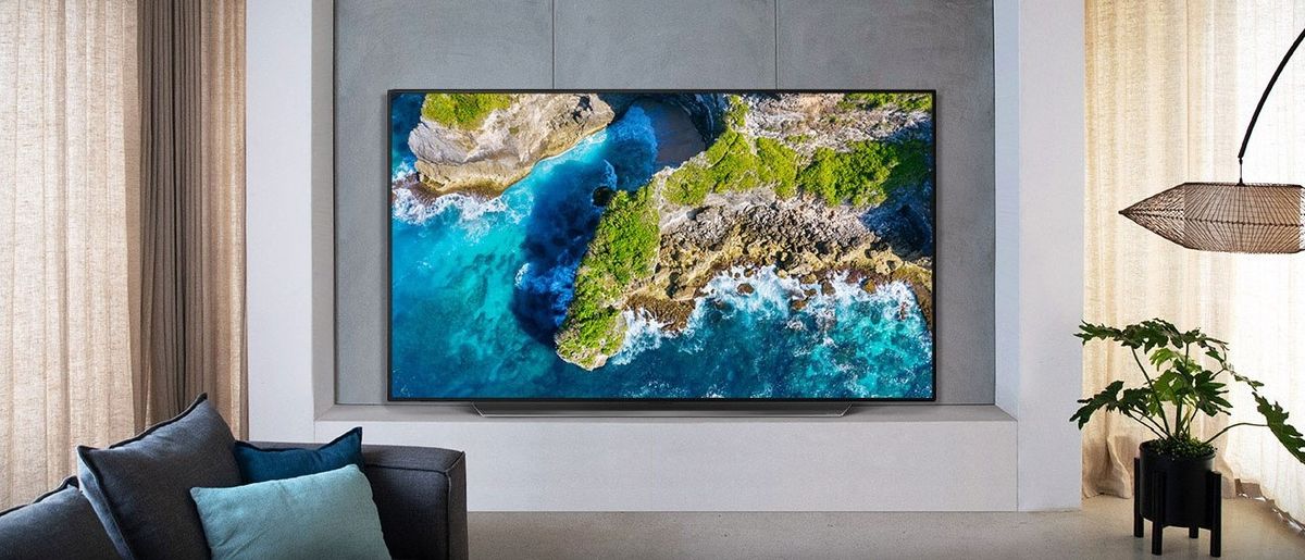 The LG CX OLED TV showing a piece of coastline, at back of stylish living room