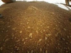 This low-resolution view of the floor of Mars&rsquo; Jezero Crater and a portion of two wheels of NASA&rsquo;s Perseverance Mars rover was captured by the agency&rsquo;s Ingenuity Mars helicopter on April 3, 2021.&nbsp;It&rsquo;s the first color photo taken by Ingenuity on the Martian surface. 