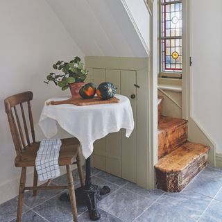 small hallway with narrow staircase and bistro table beneath the stair with vintage wooden dining chair