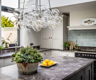 Stylish kitchen featuring a striking bubble chandelier made of clustered glass globes above a dark marble island