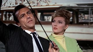 Sean Connery studies a reel of film in a boat beside Daniela Bianci in From Russia With Love.