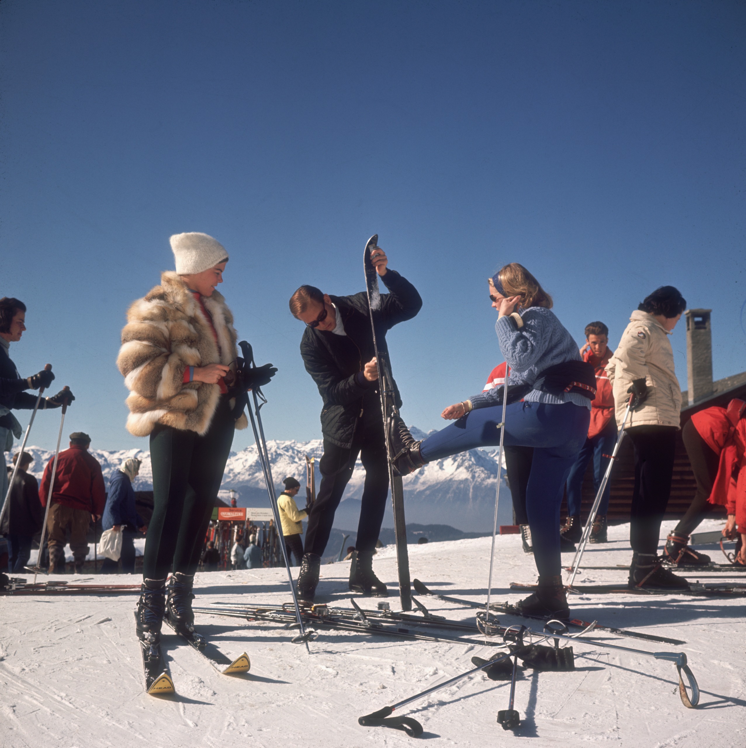 Three skiers in vintage ski gear at the top of the mountain