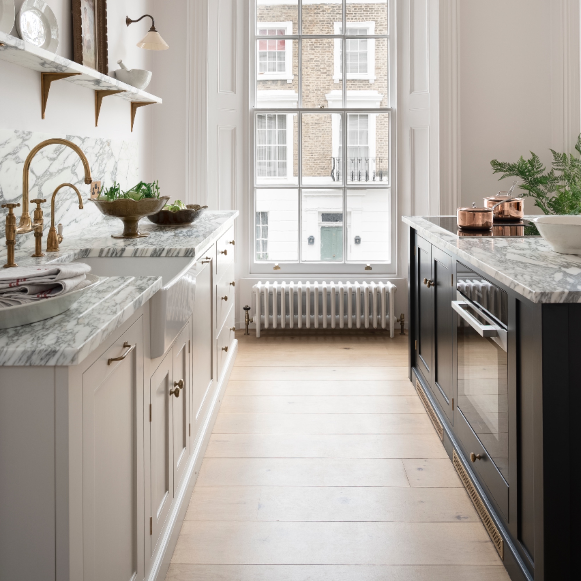 white and marble kitchen with wooden floorboards, contrasting unit colours, open shelving