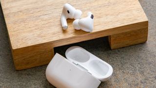 Apple AirPods Pro ligger på en træklods ved siden af opladningsetuiet