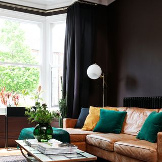 A black-painted living room with matching curtains and a brown leather sofa