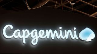 The Capgemini logo (cursive letters that read Capgemini next to a stylised shape that resembles a clover or water drop) lit up in blue against a dark wall.