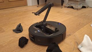 Roborock Saros Z70 robot vacuum picking up a sock with its pincer arm