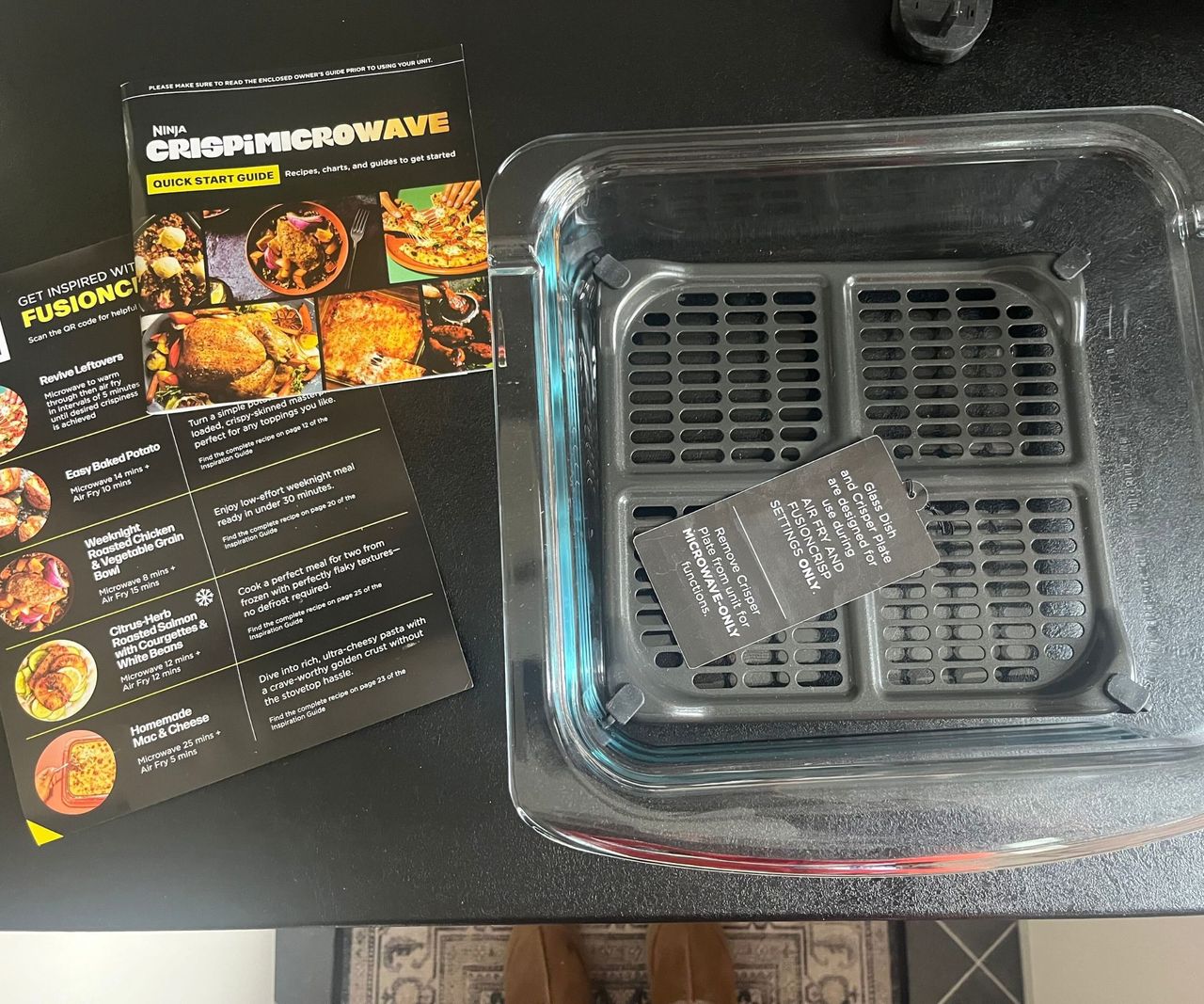 A glass air fryer dish with a crisper tray on a black counter
