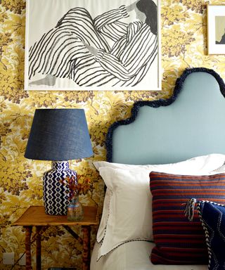A yellow bedroom with a bed with blue headboard and white bedding
