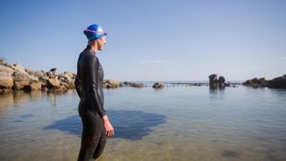A fit female triathlete stands in the cold sea water of Camps Bay, South Africa