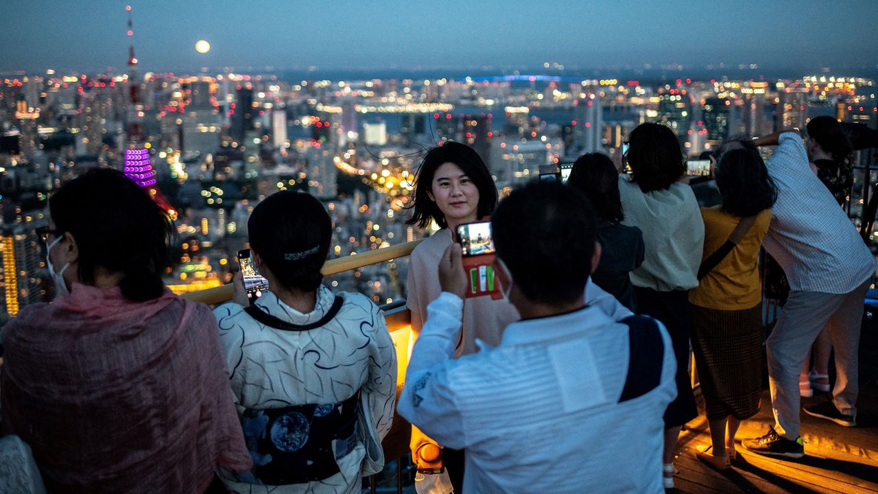 People watch the full moon on the observation deck of Roppongi Hills Mori Tower, during a harvest-moon viewing event in Tokyo on September 10, 2022.