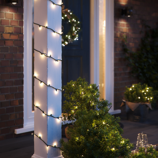 close up of lights on pillar and tree outside a house