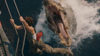 A Spinosaurus lunges at a dangling human in Jurassic World Rebirth.