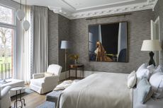 grey and pale blue bedroom with grey textured wallpaper, artwork, armchairs, pendants, floor lamps, bay window 