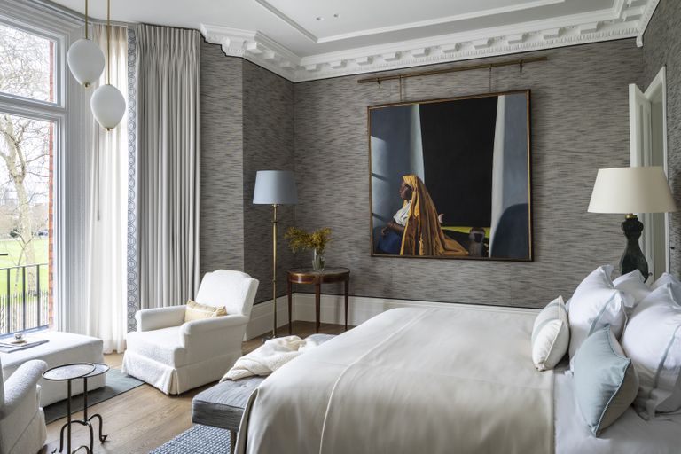 grey and pale blue bedroom with grey textured wallpaper, artwork, armchairs, pendants, floor lamps, bay window 