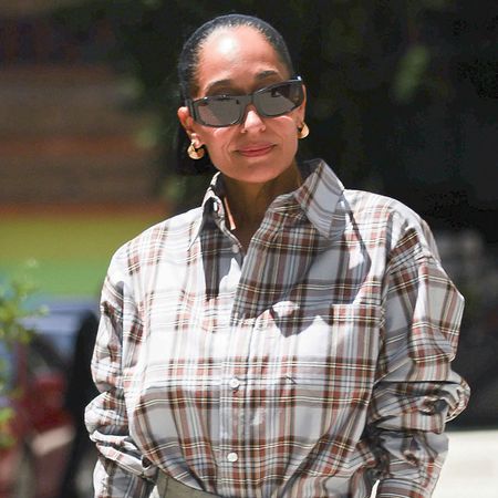 Tracee Ellis Ross wearing a plaid button-down, gray shorts, and gold mule heels