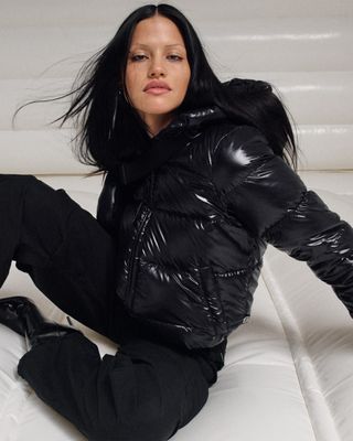 A photo of Gabriette Bechtel posing in a hooded black hi-gloss Super Puff.