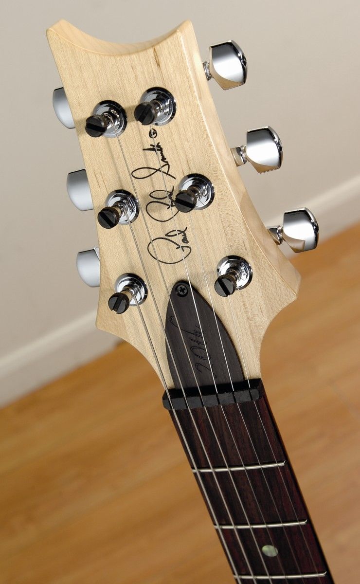 The maple headstock creates a contrast with the guitar's rosewood fingerboard