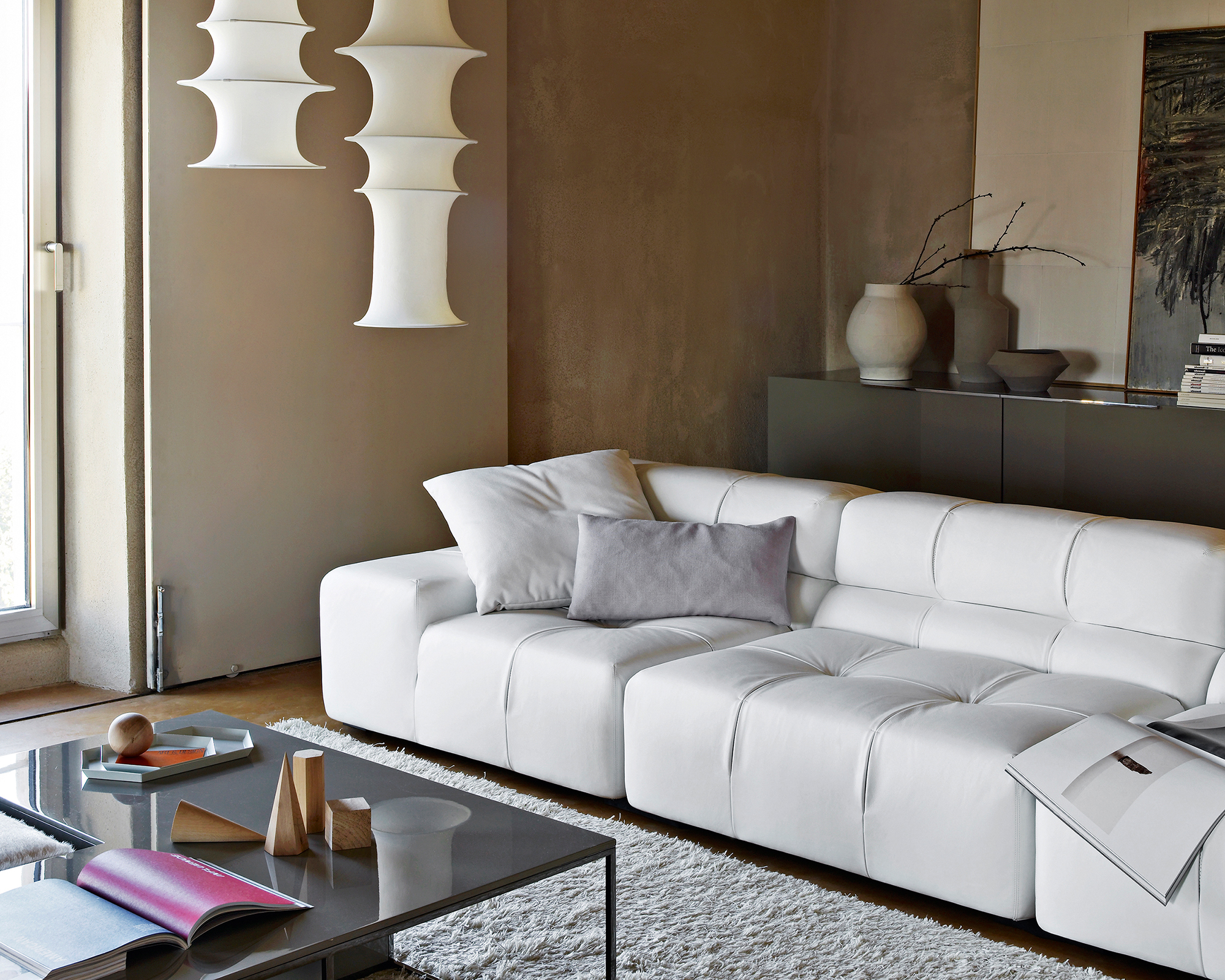 low white sofa in a brown living room with white pendant lights above it