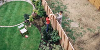 Two neighbours talking over garden fence