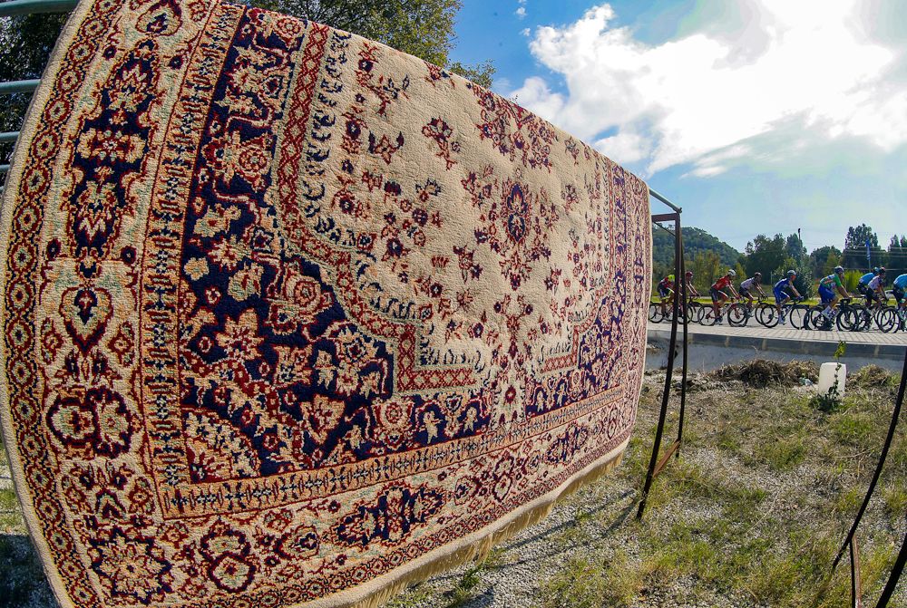 A carpet hangs along the route as the peloton passes