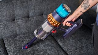 the dyson gen5detect cordless stick vacuum in prussian blue and copper, showing its cleaning head and attachment tools