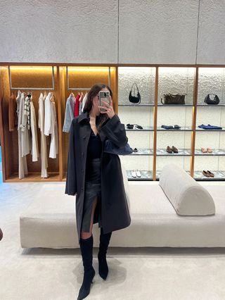 Eliza Huber wearing a brown car coat, leather skirt, and suede tall boots during Milan Fashion Week.