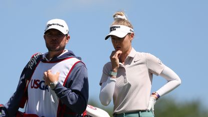 Nelly Korda stands with one hand on her hip and the other by her mouth next to caddie Jason McDede at the 2024 US Women's Open