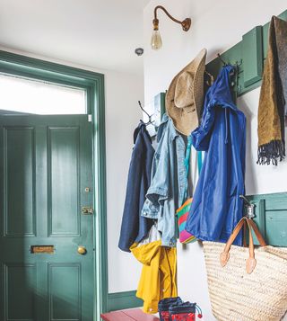 Coats hung in a hallway with white walls and green woodwork