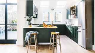 Kitchen painted in dark green and white to make the smaller space feel bigger