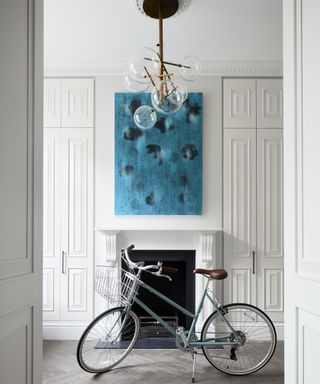 A hallway lighting idea with white walls, a blue painting and sputnik chandelier