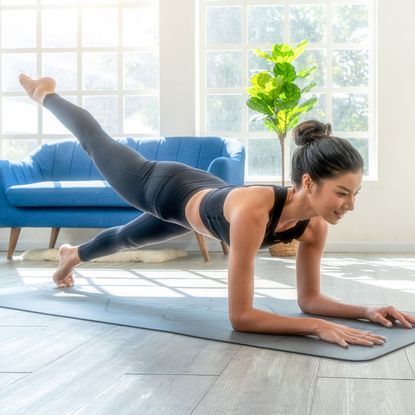 A woman at home in gym gear practicing Pilates exercises for beginners