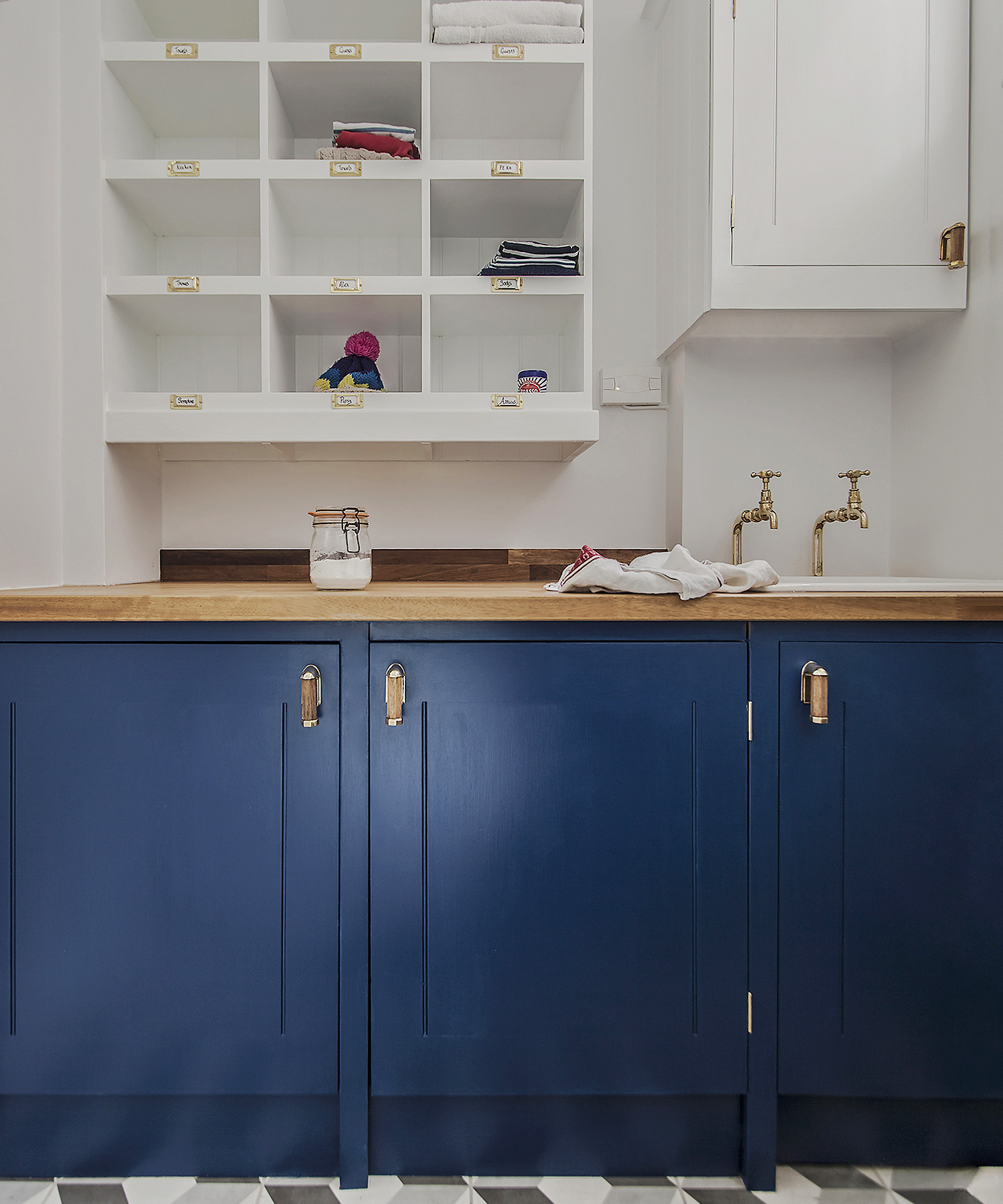 A utility room with blue cabinets and simple, white box shelving