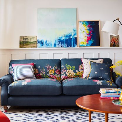 floral design blue sofa with cushions blue strip carpet and wall paintings