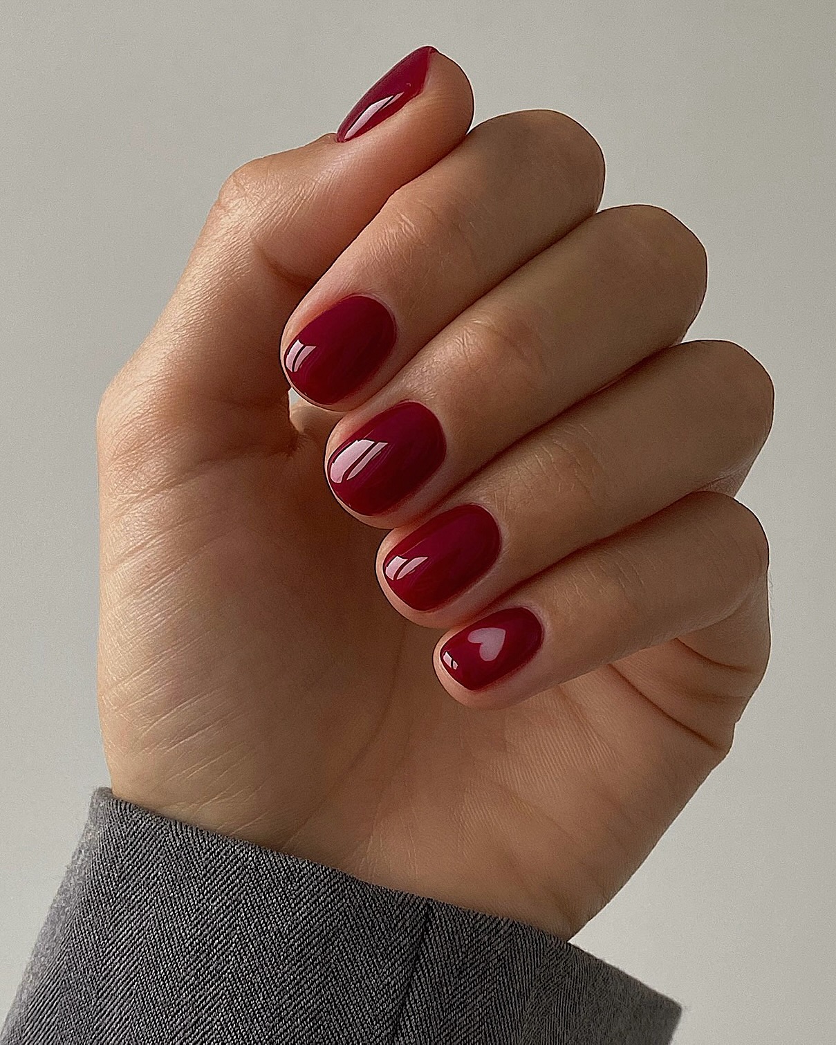 A cherry red manicure with a negative space heart design by Mateja Novakovic