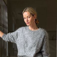 a woman wearing a gray sweater, green leather skirt, and snakeskin heels