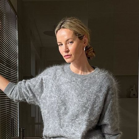 a woman wearing a gray sweater, green leather skirt, and snakeskin heels