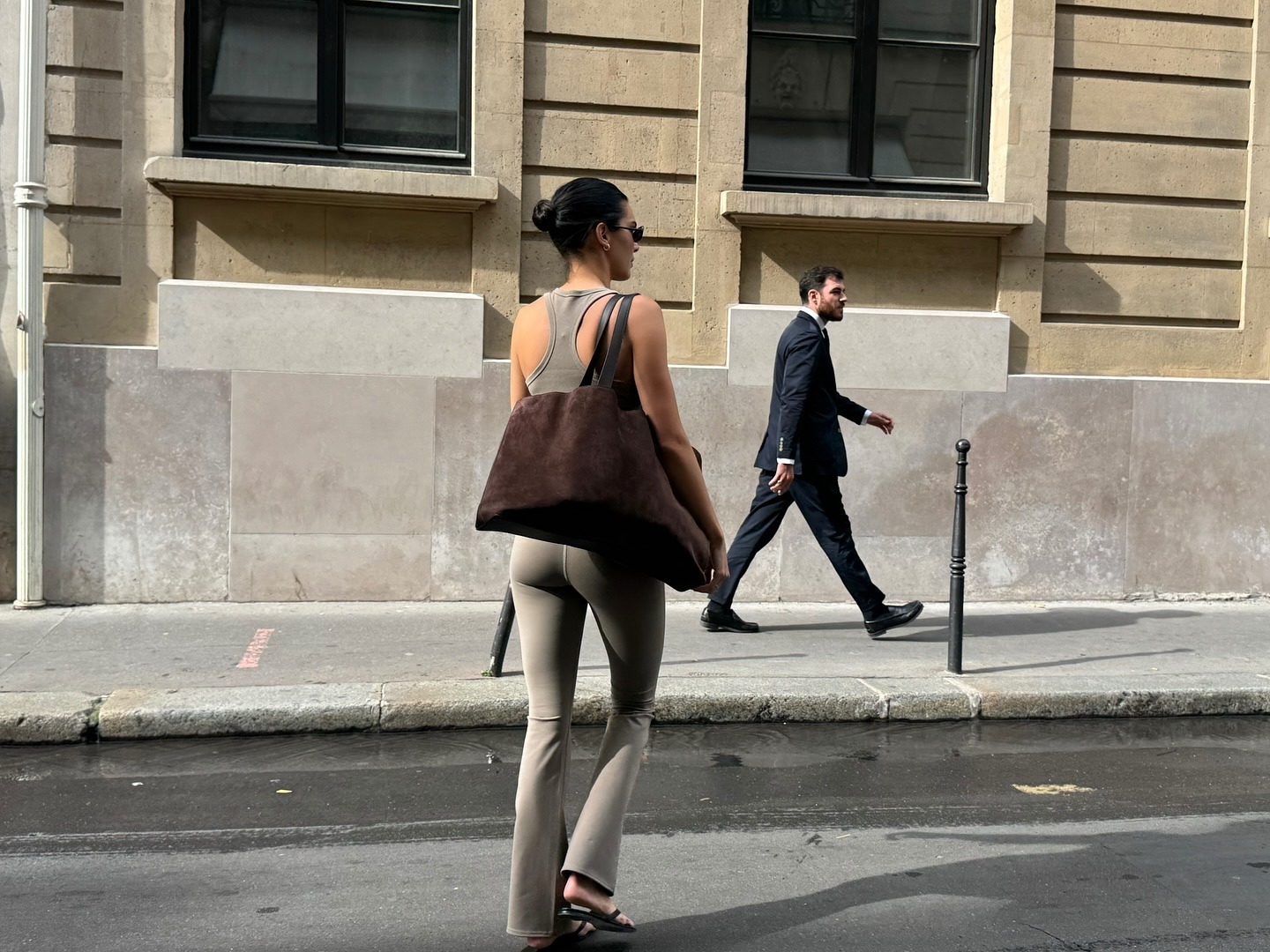 Kendall wears a taupe tank, taupe leggings, and a brown suede tote bag.