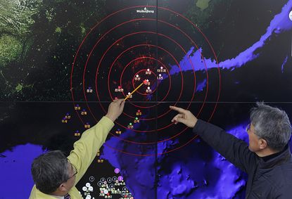 Korean scientists look at seismic waves on a map.