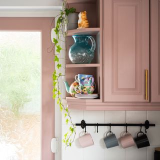 kitchen with pink cupboard and coffee mugs