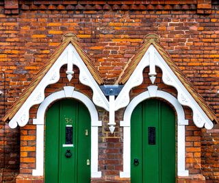 pair of red brick homes with matching green front doors