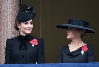 Kate Middleton and Duchess Sophie wearing black dresses and hats smiling at each other on Remembrance Day