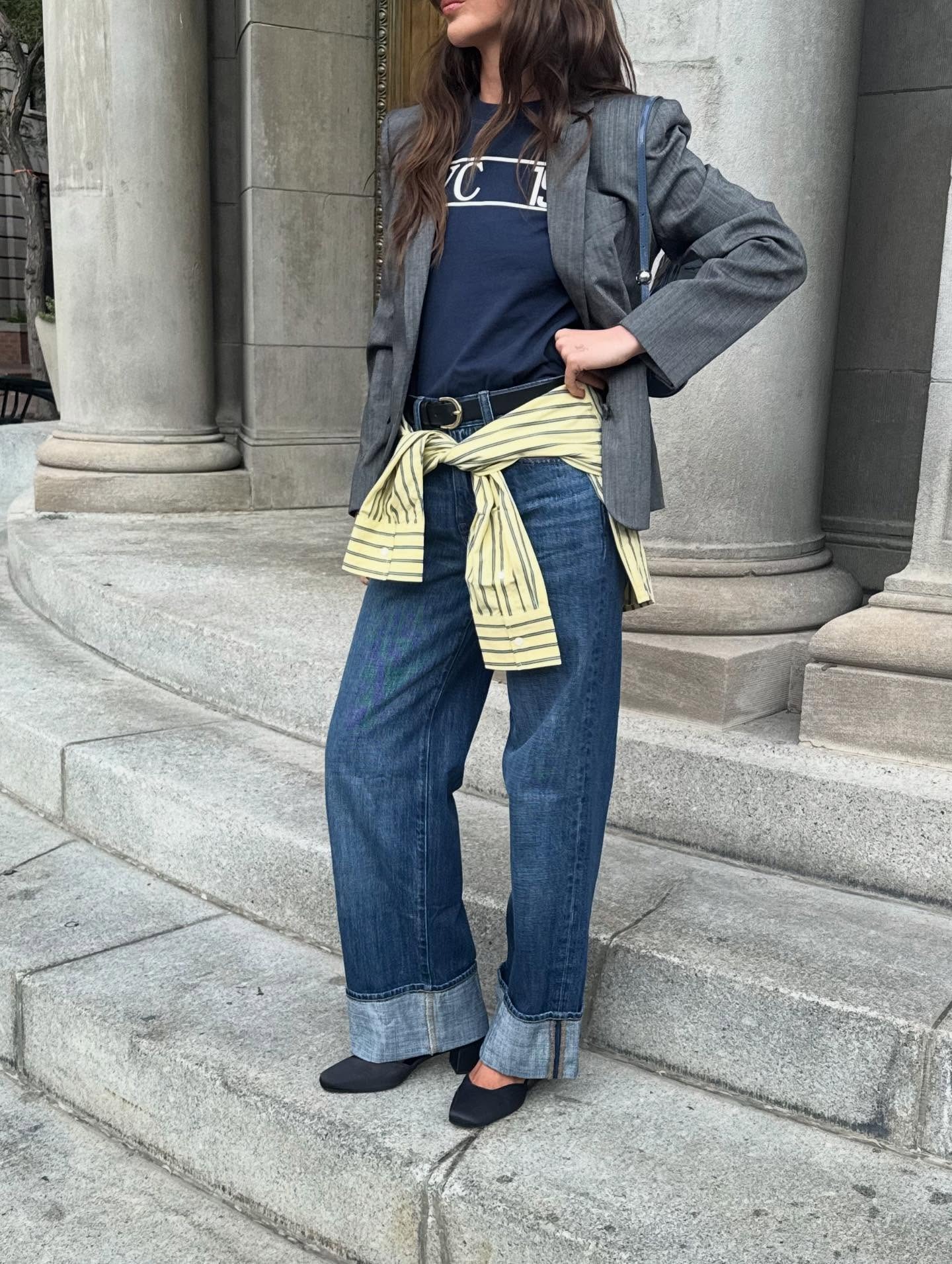 Influencer @makenna_alyse wears a navy t-shirt with a grey blazer, blue cuffed jeans and black closed-toe low-heels.