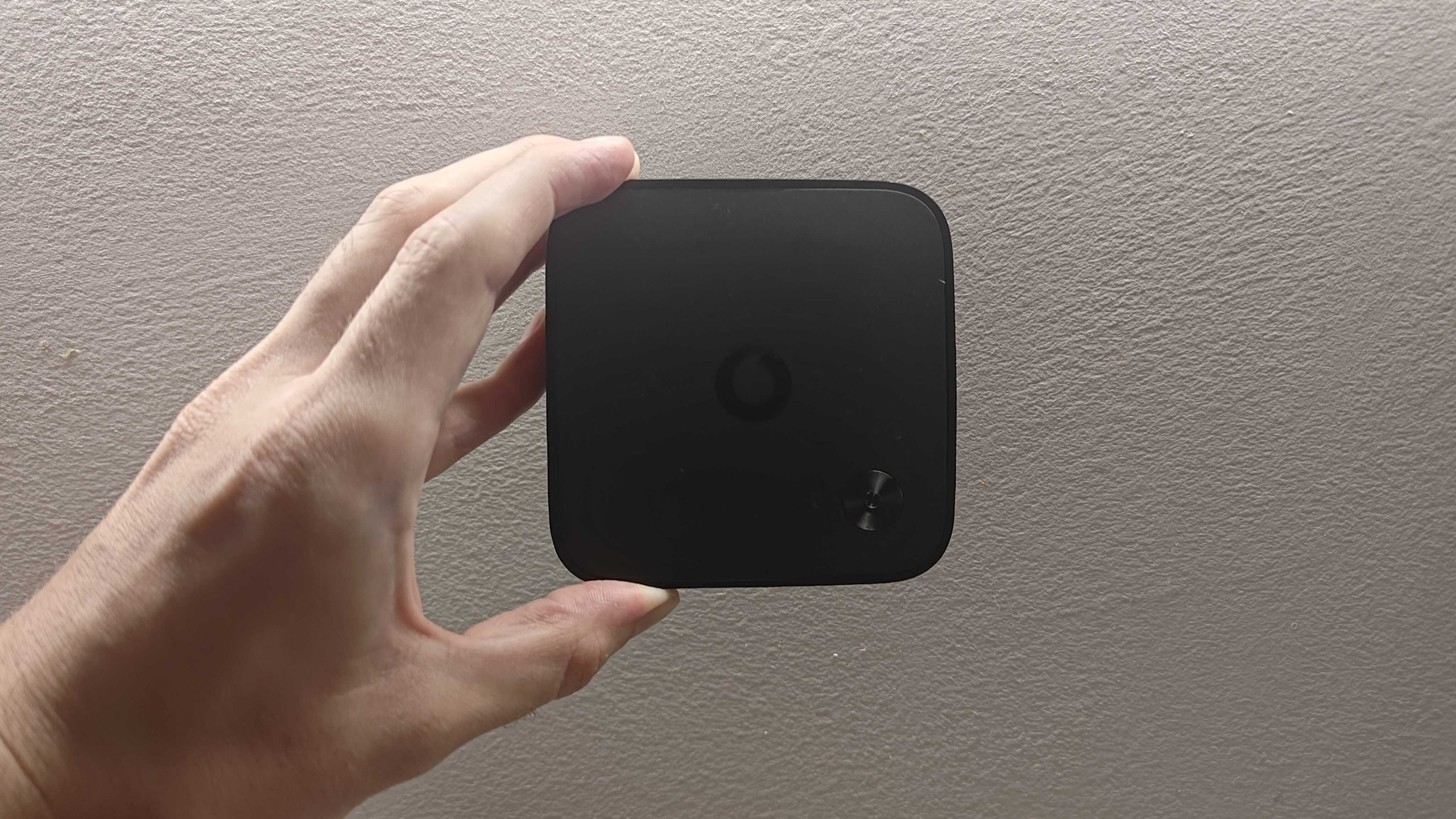 A picture of a hand holding a Vodafone TV streaming box