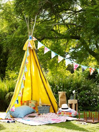yellow tipi and bunting over picnic rug
