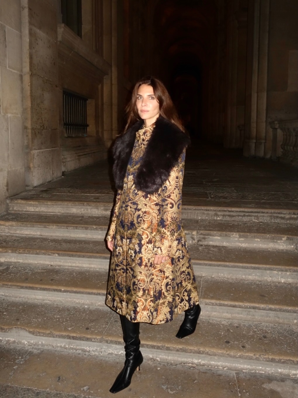 An image of @jen_wonders wearing slouchy boots with a fur-trimmed ornate coat.