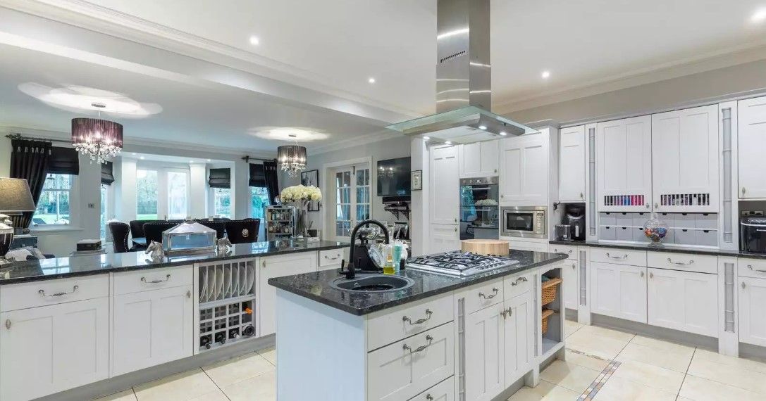 The kitchen island has a black marble surface and the other storage facilities are white