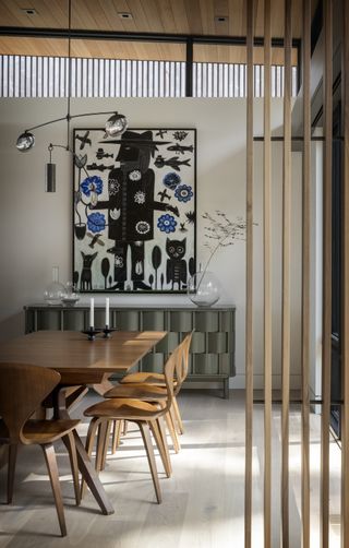 Dining room with wooden dining chairs and a large piece of art