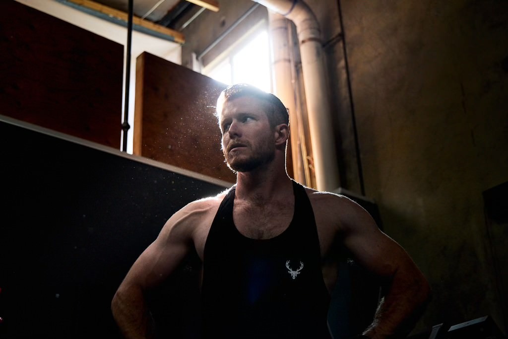 Man stands in vest top in industrial setting