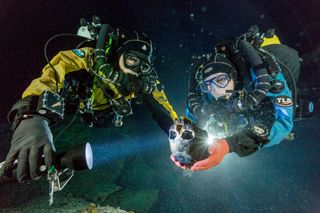 divers examine human skeleton found in underwater cave